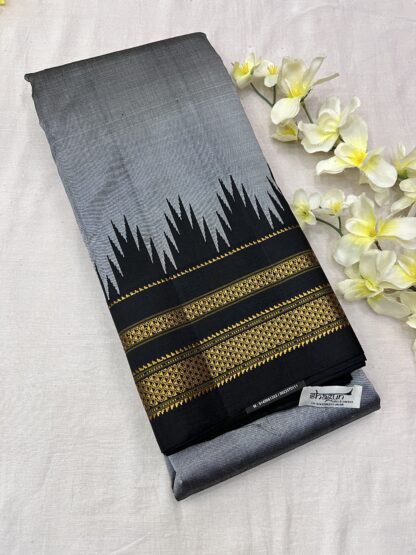 A stunning Grey and Black Pure Silk Ilkal Saree with a temple-inspired gold zari border, neatly folded and adorned with floral accents.