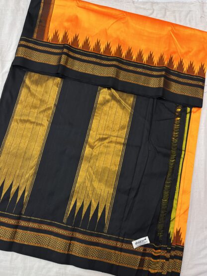 Fully spread pure silk saree in sunset orange and midnight black, showcasing intricate golden zari work, temple border design, and a grand woven pallu.