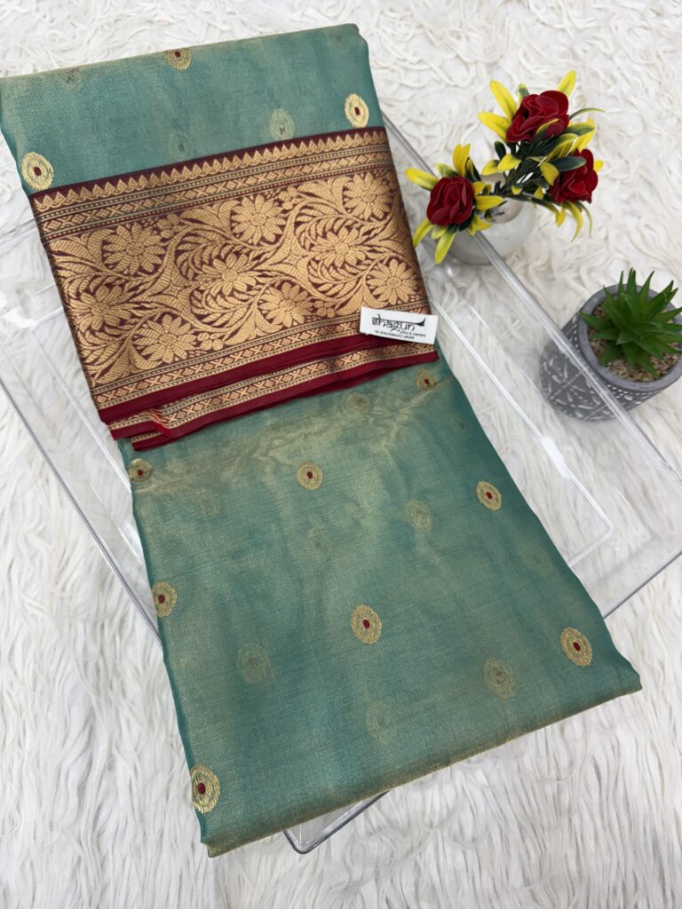 Folded emerald Chanderi tissue silk saree with intricate golden zari border and floral detailing